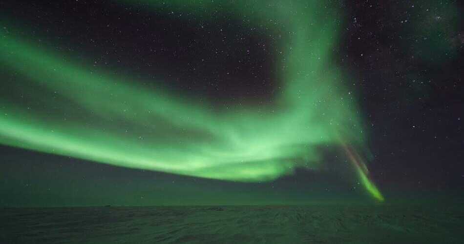 Aurora Australis entsteht, wenn kosmische Strahlung (meist geladene Sonnenteilchen) auf die Magnetosphäre der Erde trifft.